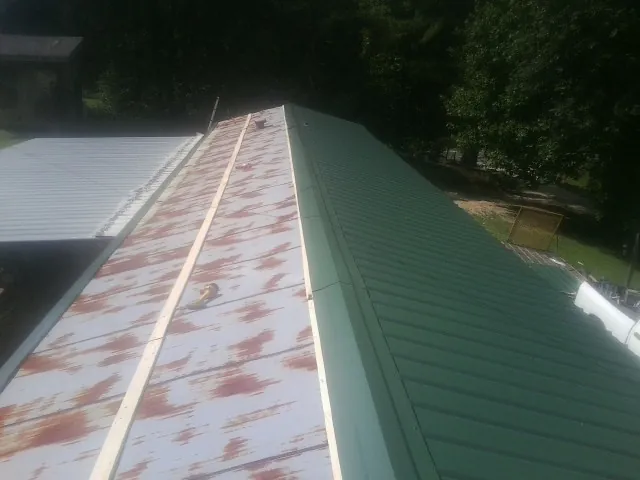Old rusted panels beside newly installed green metal roofing — Wind Damage Roof Repair by Roofing Brothers in Beulaville